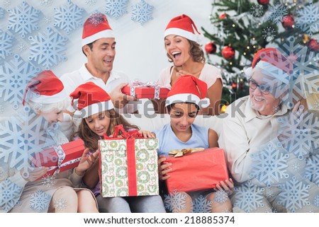 Excited family exchanging gifts at christmas against snowflake frame