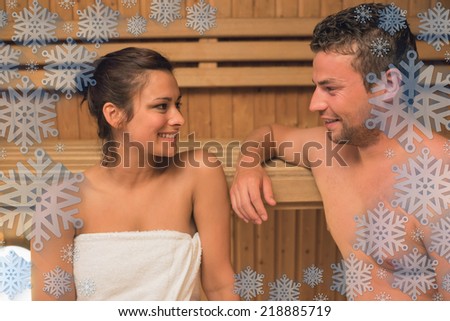Smiling couple relaxing in a sauna and chatting against snowflake frame