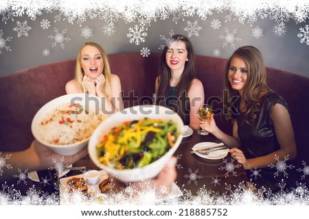Happy friends looking at the salad against fir tree forest and snowflakes