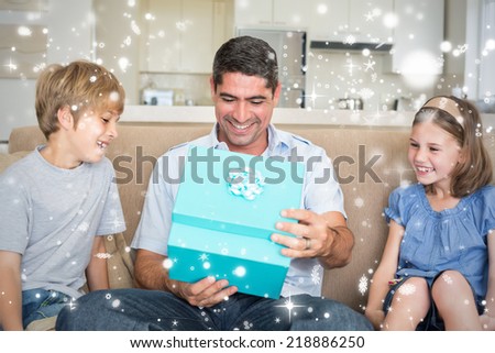 Composite image of Father opening gift given by children on sofa against snow falling