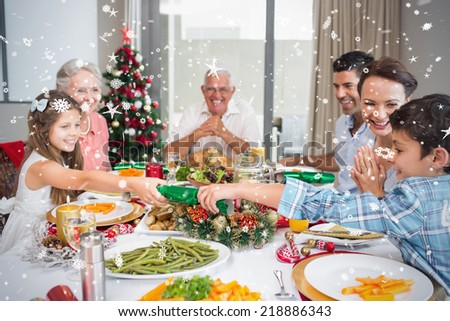 Cheerful family at dining table for christmas dinner against snow falling