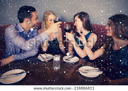 Composite image of Smiling friends clinking wine glasses against snow falling