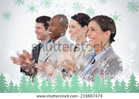 Side view of clapping sales team standing together against snowflakes and fir trees in green