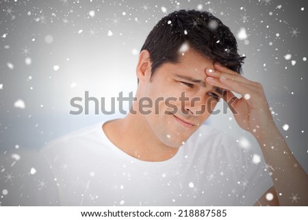 Worried man having a headache sitting in his bedroom against snow falling