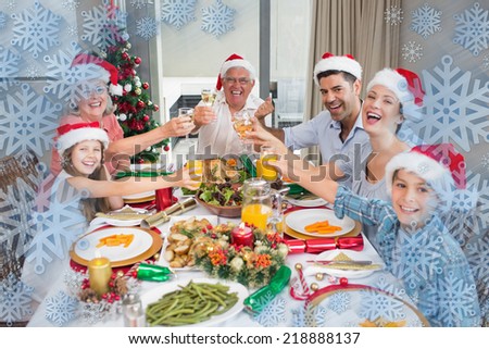 Family in santas hats toasting wine glasses at dining table against snowflake frame
