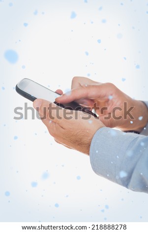 Composite image of Hands using mobile phone with snow falling