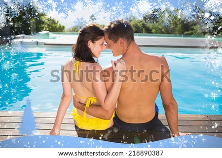 Couple sitting by swimming pool on a sunny day against snow