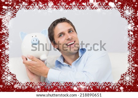 Handsome casual man with piggy bank in living room against snow