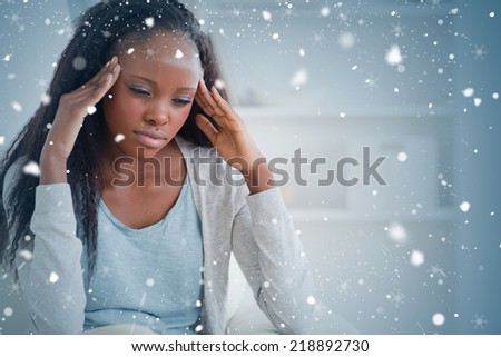 Composite image of woman experiencing a headache against snow falling