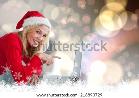 Happy festive blonde with laptop against light glowing dots design pattern