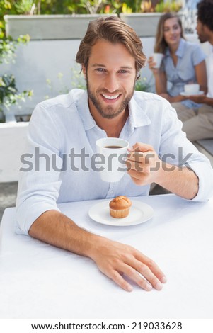 Happy man having coffee and muffin outside at the coffee shop