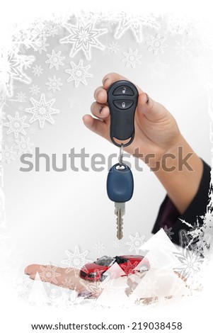 Composite image of Woman holding key and small car in a christmas frame