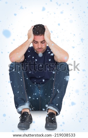 Sitting upset man with head between hands against snow falling