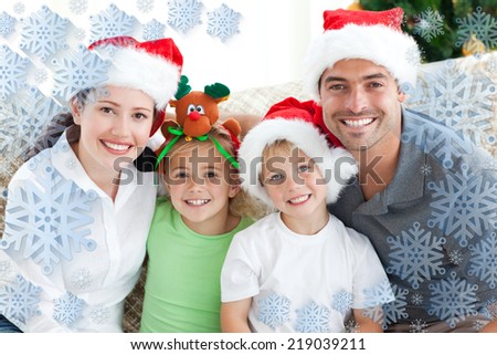 Happy family with christmas hats sitting on the sofa against snowflake frame