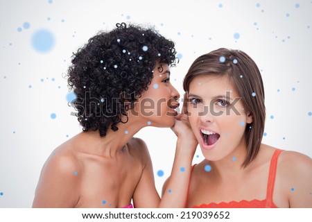 Teenage girl telling a surprising secret to a friend against snow falling