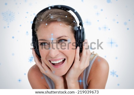 Close up of a smiling woman listening to music against snow falling