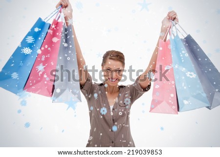 Smiling woman raising her shopping bags against snow falling