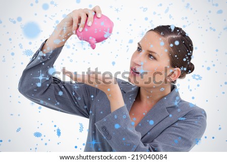 Bank clerk emptying piggy bank against snow falling
