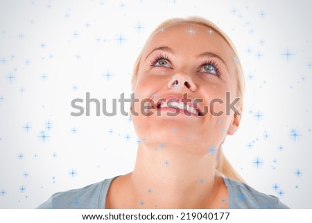 Smiling blond woman looking at the ceiling against twinkling stars