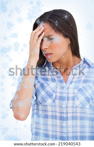 Woman with a headache and hand on forehead against snow falling