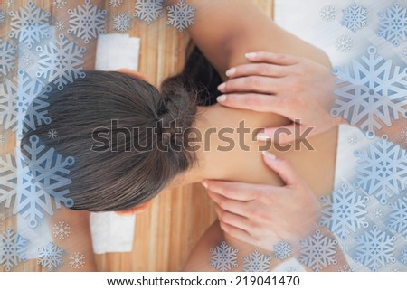 Beautiful brunette enjoying a shoulder massage against snowflake frame