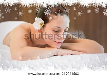 Beautiful woman lying on massage table at spa center against fir tree forest and snowflakes
