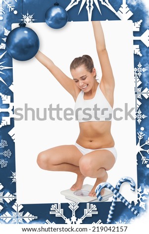 Happy attractive woman crouching on a scales against christmas frame