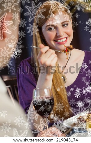 Pretty woman smiling at her husband during dinner against snowflakes on silver