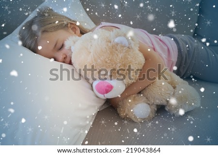 Girl sleeping on sofa with stuffed toy against snow falling