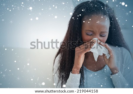Composite image of close up of woman blowing her nose on couch against snow
