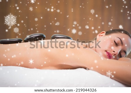 Beautiful woman receiving stone massage at health farm against snow falling