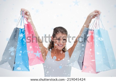 Composite image of woman holding shopping bags against snow falling