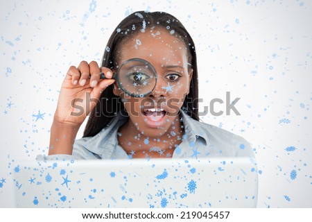 Businesswoman using a magnifying glass to look at her notebook against snow falling