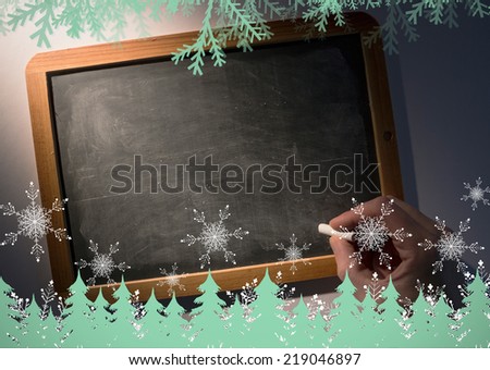 Frost and fir trees in green against hand holding chalk over chalkboard