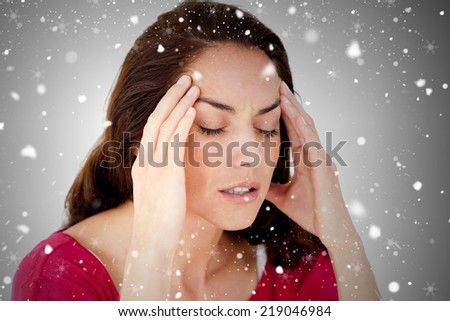 Composite image of beautiful woman having a headache against snow falling