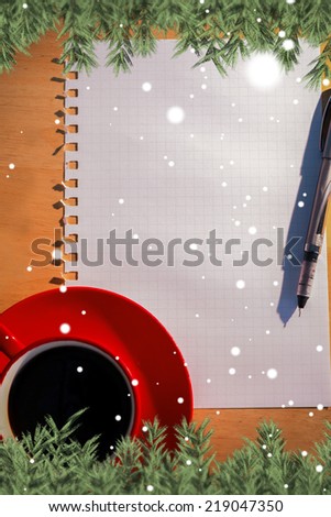 Snow falling against overhead of graph paper coffee and pen
