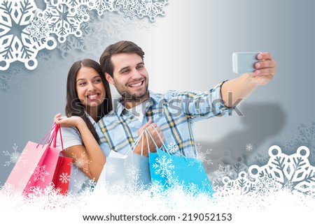 Happy couple taking a selfie against white snow flake frame on silver