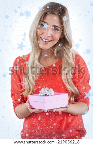 Composite image of Blonde woman receiving a gift with snow falling