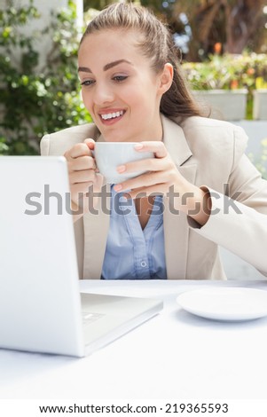 Beautiful businesswoman having a coffee using laptop outside at the coffee shop