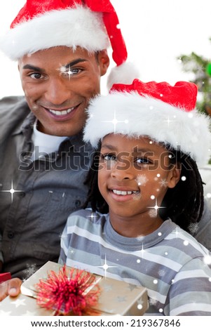 Composite image of Portrait of an father and son holding a Christmas gift with snow falling