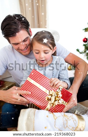 Composite image of Surprised little girl holding a Christmas present with her father with twinkling stars