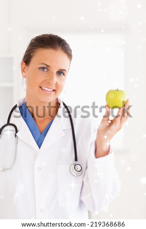 Gorgeous brunette doctor looking at a green apple with snow falling