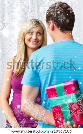 Composite image of cute boyfriend giving a present against snowflakes