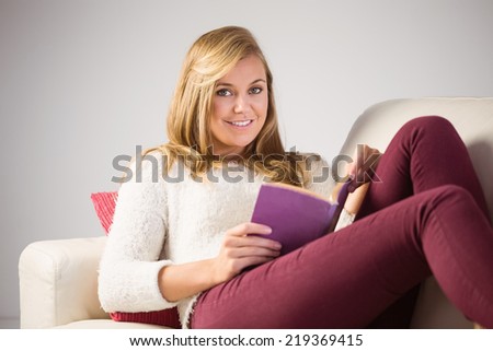 Pretty blonde relaxing on the couch with book at home in the living room