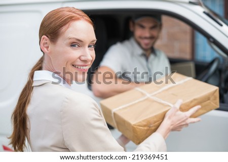 Delivery driver handing parcel to customer in his van outside the warehouse