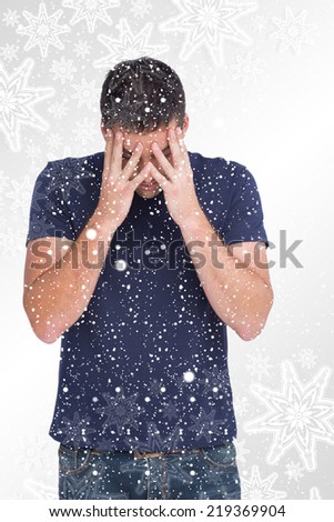 Upset man standing with his head in hands against snowflakes on silver
