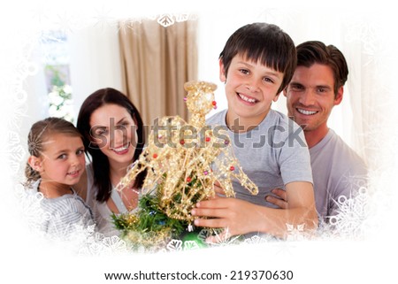 Happy little boy decorating a Christmas tree with his family against frost frame
