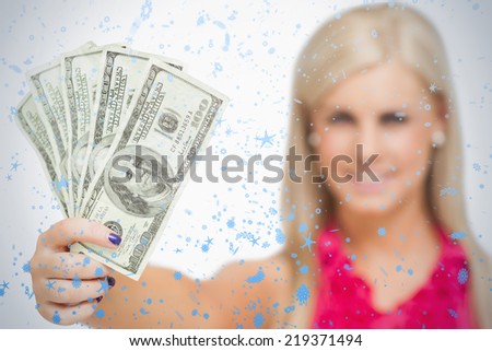 Beautiful blonde holding 100 dollars banknotes against snow falling