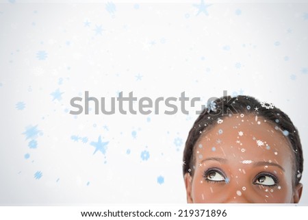 Close up of woman looking upwards diagonally on white background against snow falling