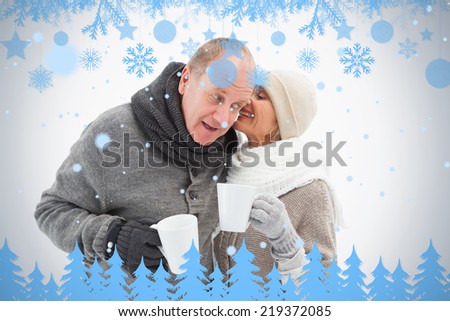 Happy mature couple in winter clothes holding mugs against snow flake frame in blue